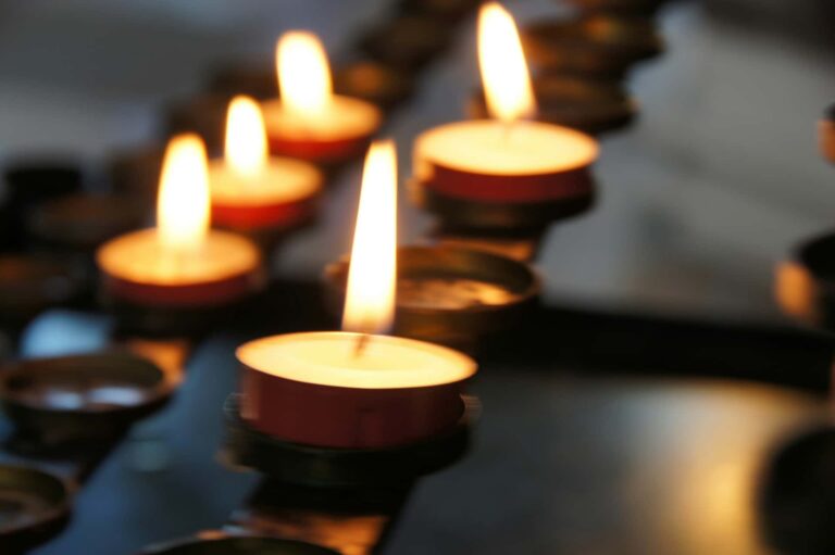 a small collection of lit tea candles sit in a darkened church